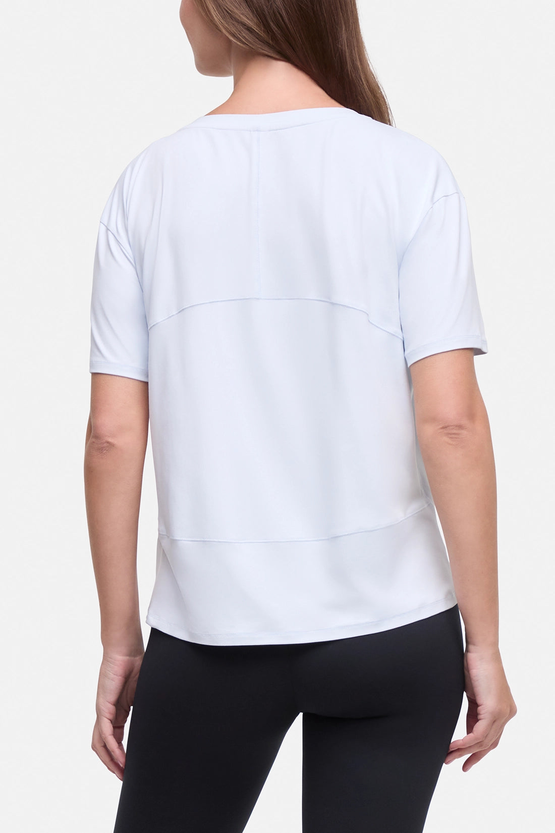 A woman shown from the back wearing a light blue short-sleeve athletic top and black leggings against a plain light background. #color_ancient-water