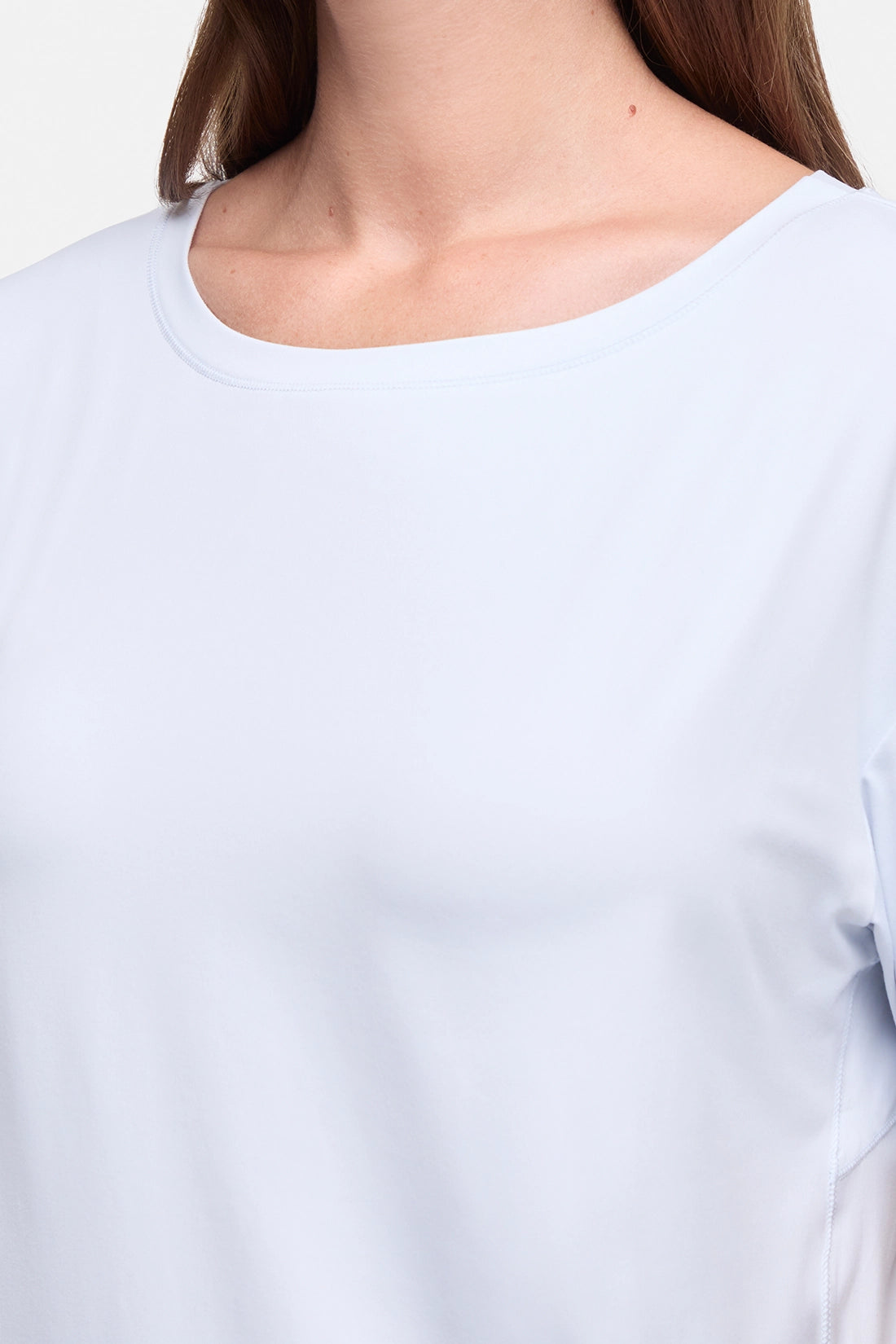 Close-up of a person wearing a plain light blue or very pale blue long-sleeve top against a clean white background. #color_ancient-water