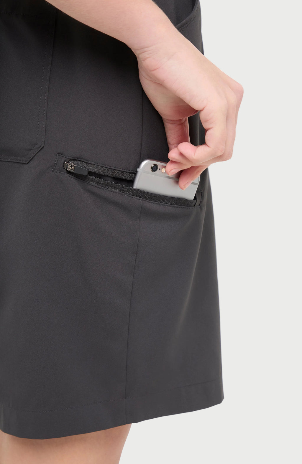 Close up side view of woman wearing dark gray shorts with side zipper pocket, standing on a white background. #color_phantom