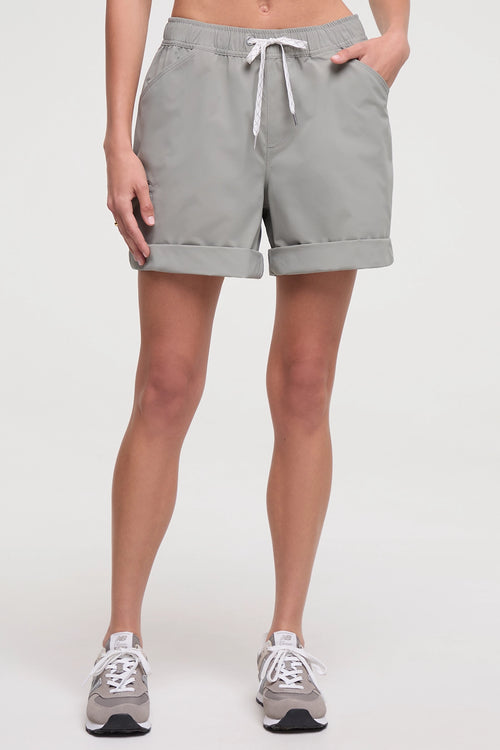 Front view of woman wearing taupe gray shorts with a white drawstring, standing on a white background. #color_shadow