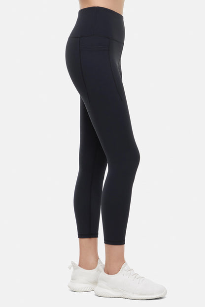 Side view of woman wearing black leggings worn by a person on a white background. 