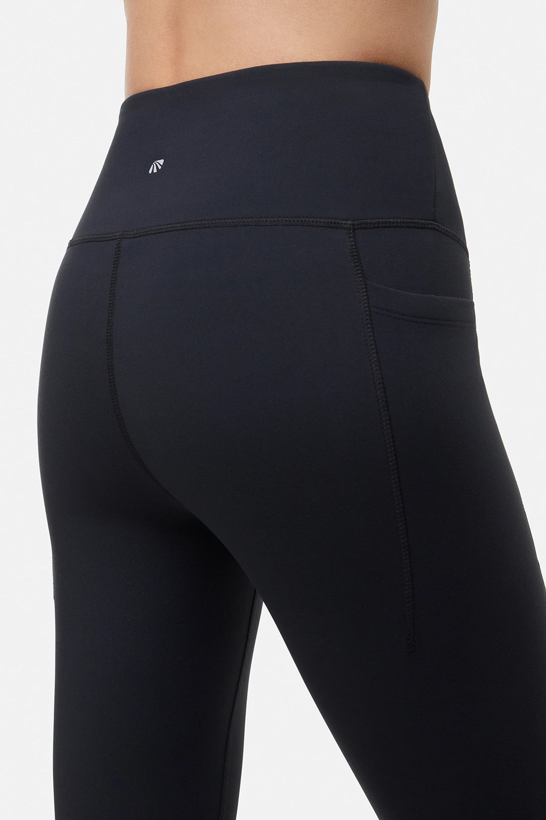 Back close up view of woman wearing black leggings worn by a person on a white background.