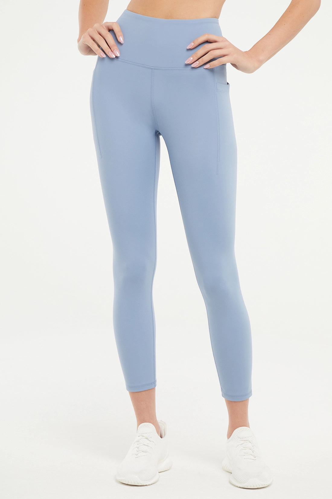 Front view of woman wearing light blue leggings worn by a person on a white background. 