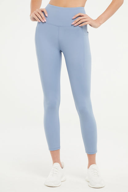 Front view of woman wearing light blue leggings worn by a person on a white background. 