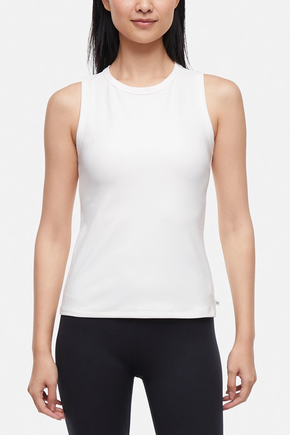 Front view of woman wearing a white ribbed-knit sleeveless tank top and black leggings on a light gray background. #color_sugar-swizzle