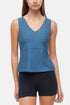 Woman wearing a blue v-neck  tank top and black shorts on a white background. 