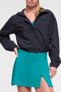 Front view of woman wearing a black jacket and teal skirt on a white background. #color_black