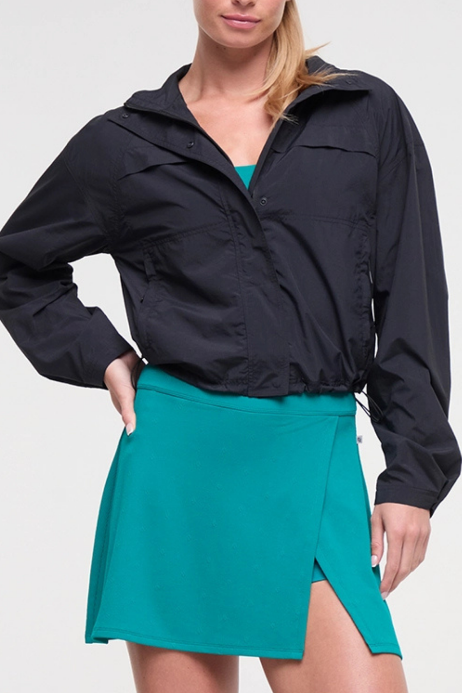 Front view of woman wearing a black jacket and teal skirt on a white background. #color_black