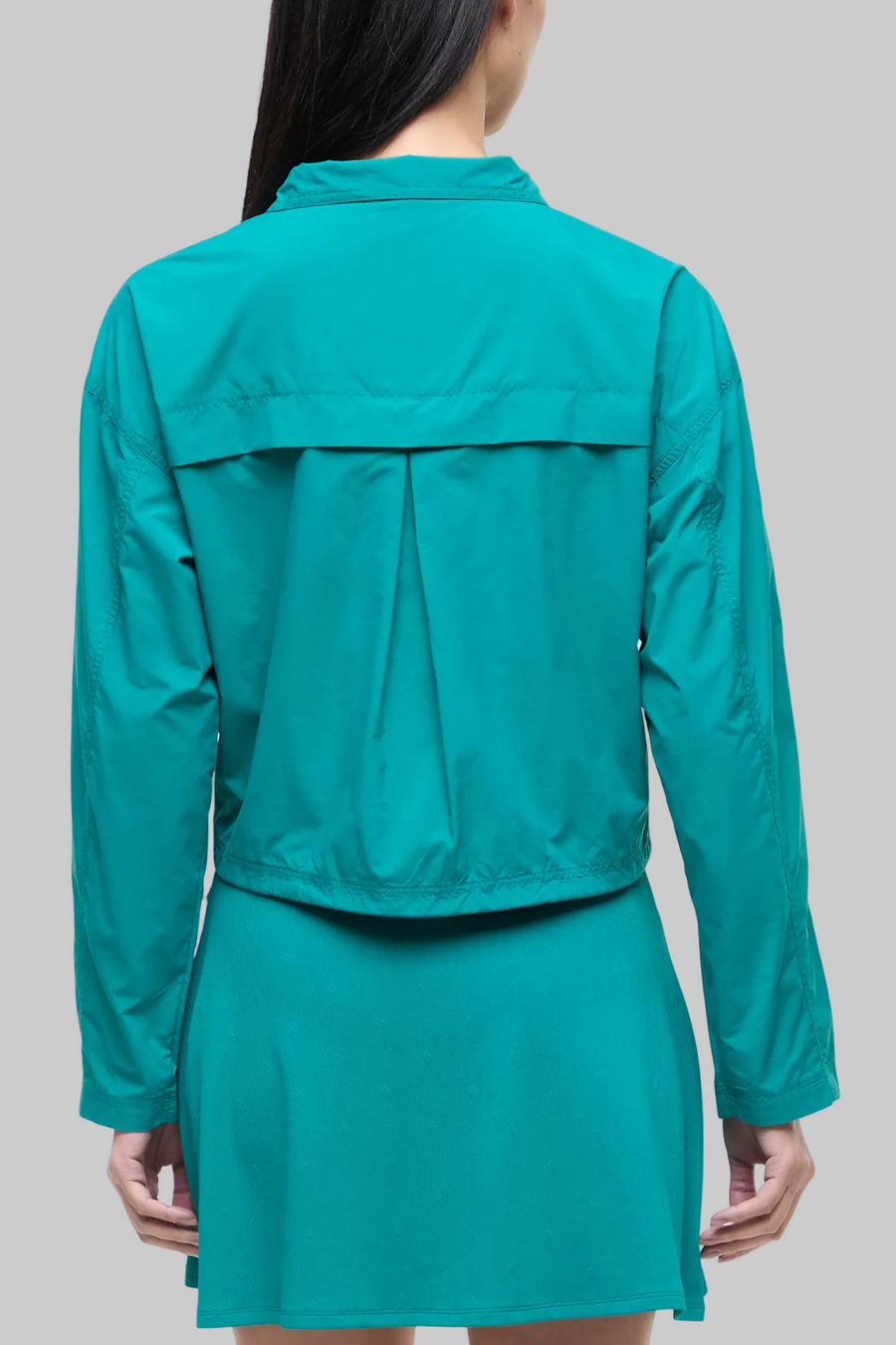 Back view of woman wearing a teal jacket and teal skirt on a white background. #color_quetzal-green