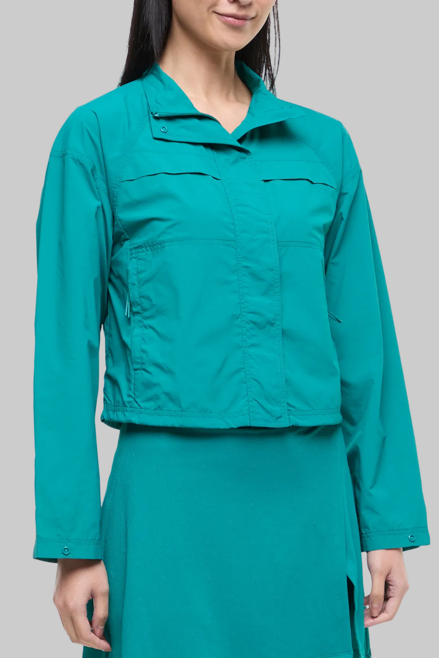 Front view of woman wearing a teal jacket and teal skirt on a white background. #color_quetzal-green