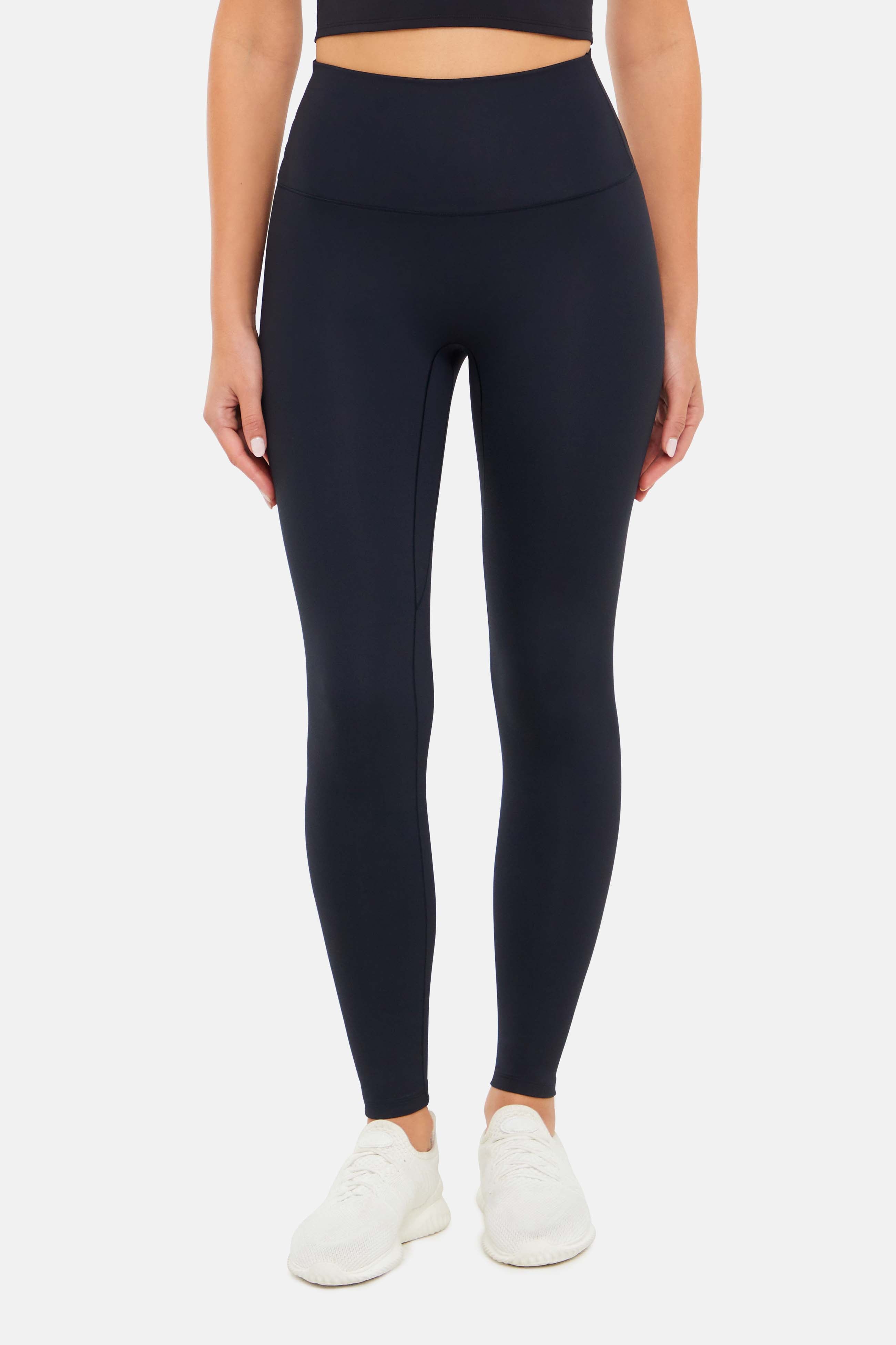 Front view of woman wearing black leggings on a white background. 