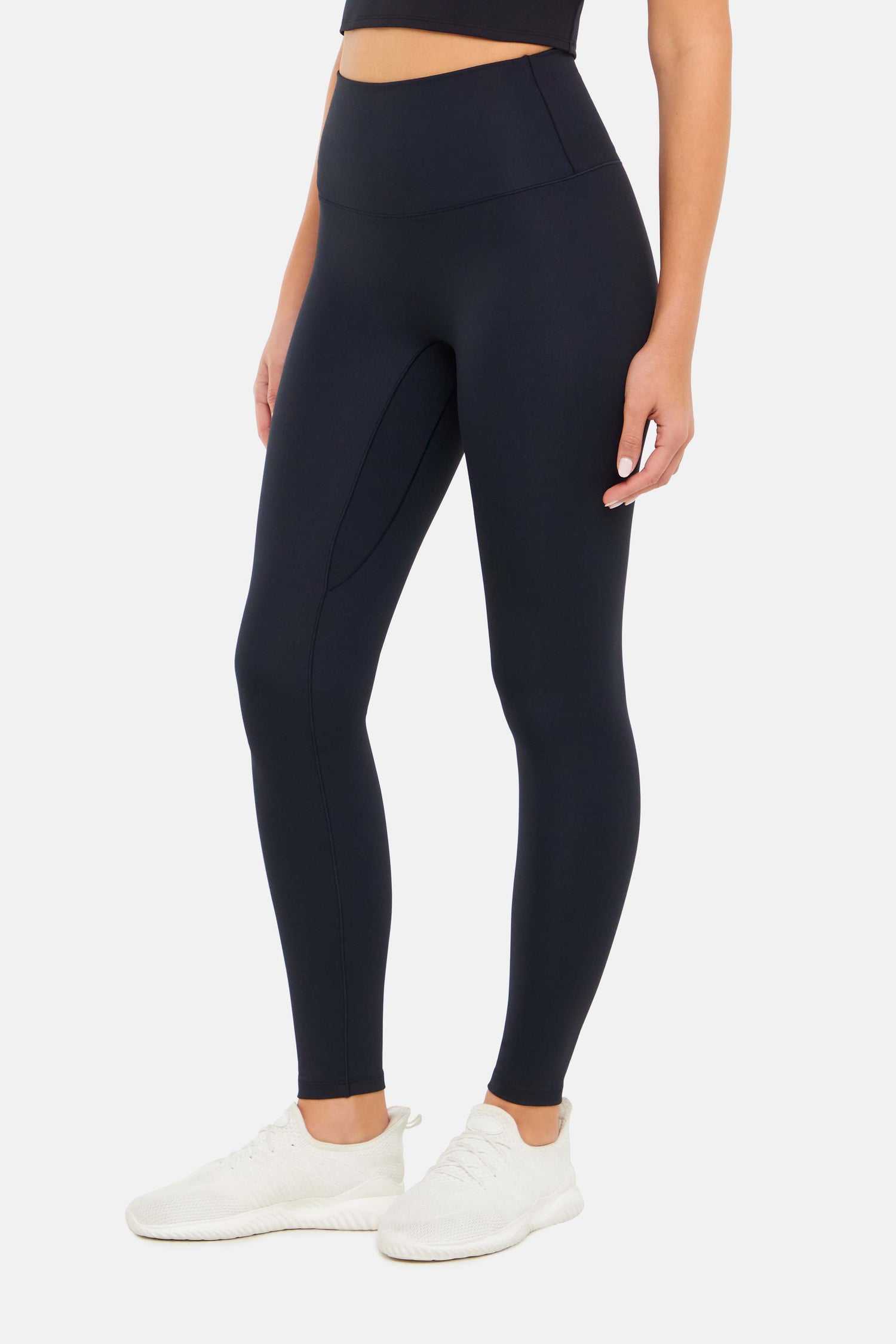 Front view of woman wearing black leggings on a white background. 