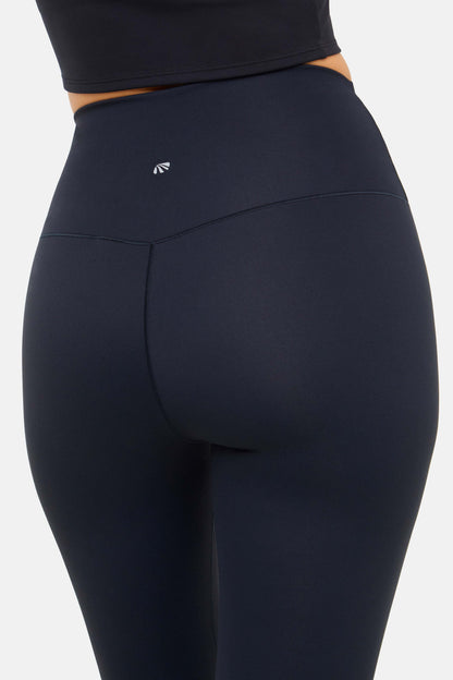 Close up back view of woman wearing black leggings on a white background. 