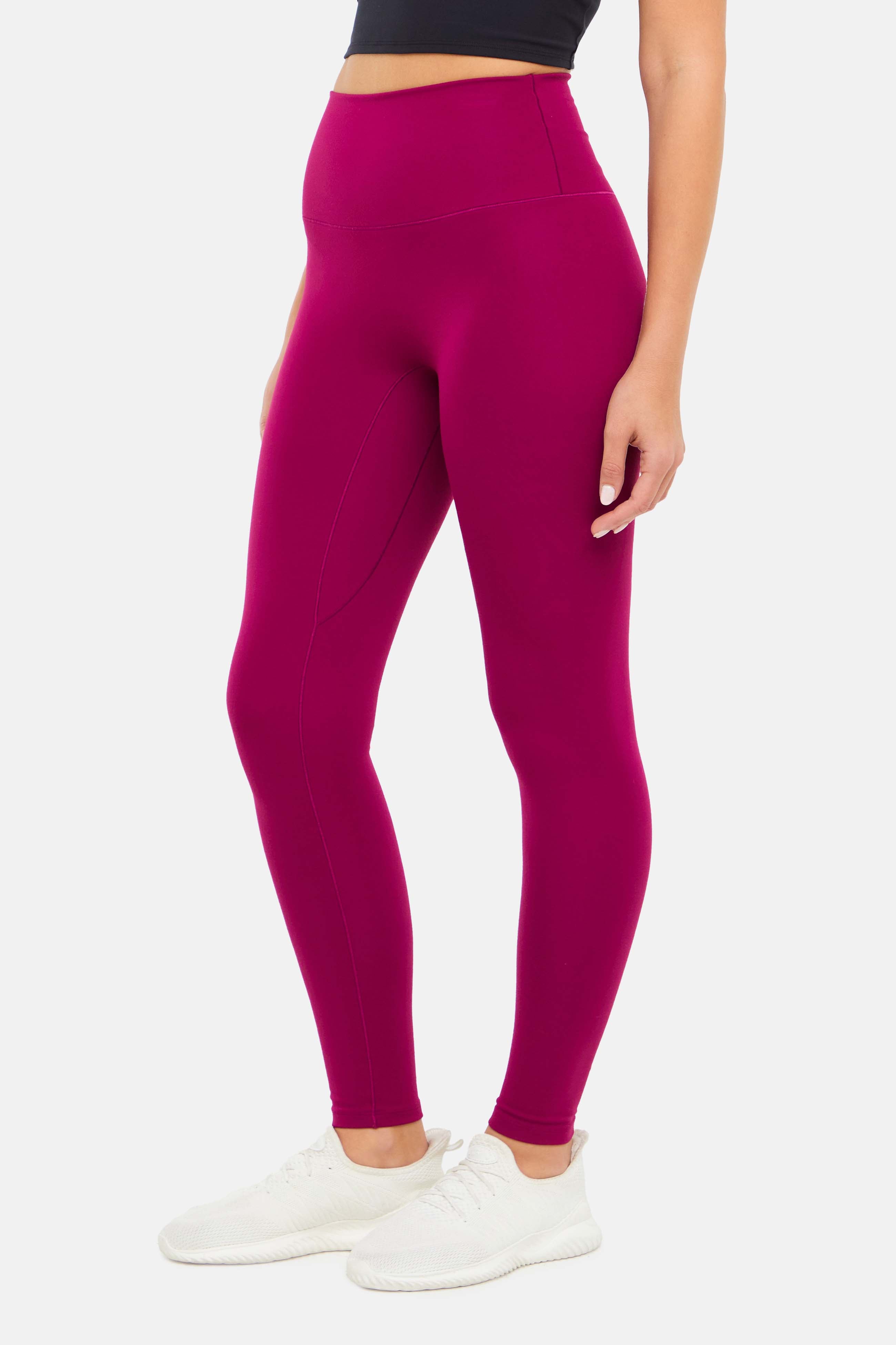 Side view of woman wearing bright burgundy leggings on a white background. 