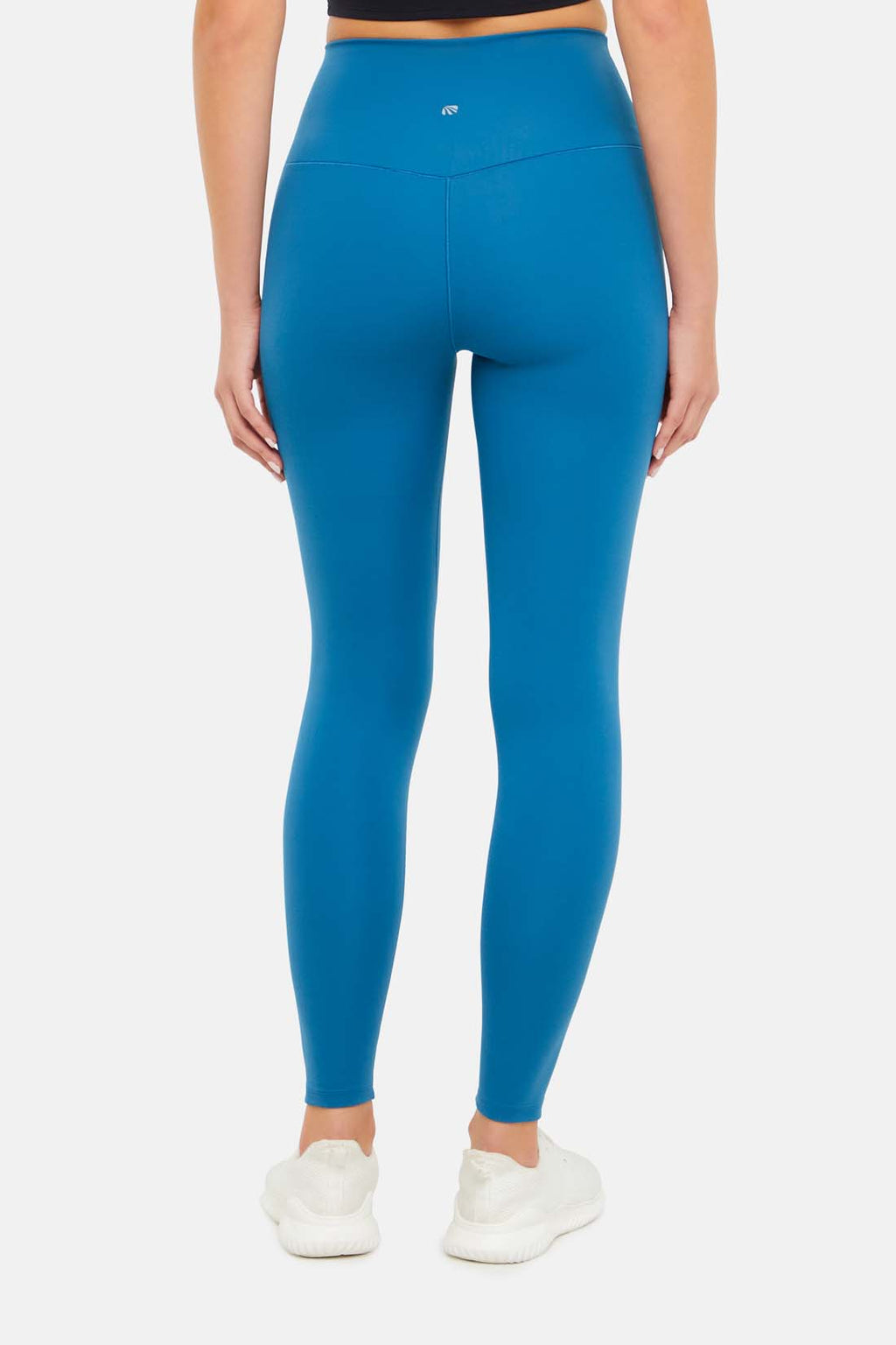 Back view of woman wearing bright blue leggings on a white background. #color_midnight