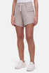 Front view of woman wearing beige  shorts with white drawstring waist and side pocket and white sneakers on a white background. 