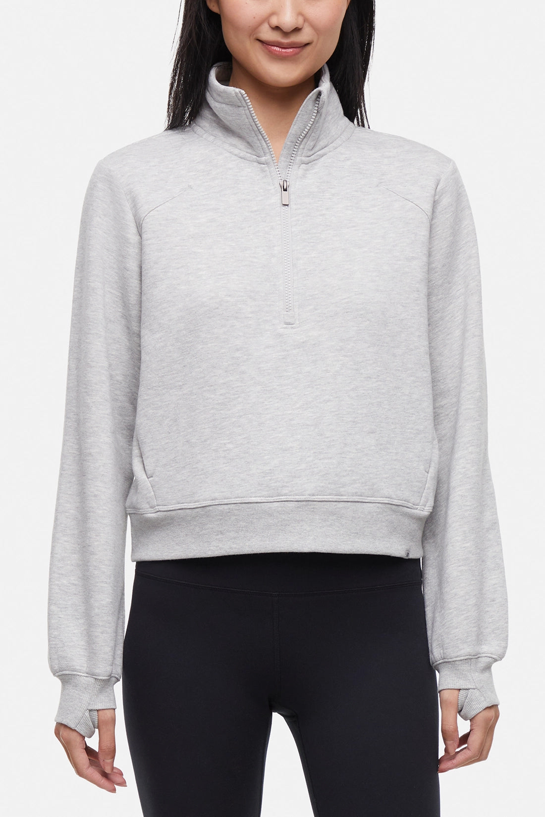 Front view of woman wearing heather gray half-zip pullover with thumbholes  on a white background. 