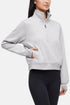 Front view of woman wearing heather gray half-zip pullover with thumbholes  on a white background. 
