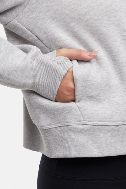 Close up view of woman wearing heather gray half-zip pullover with thumbholes  on a white background. 