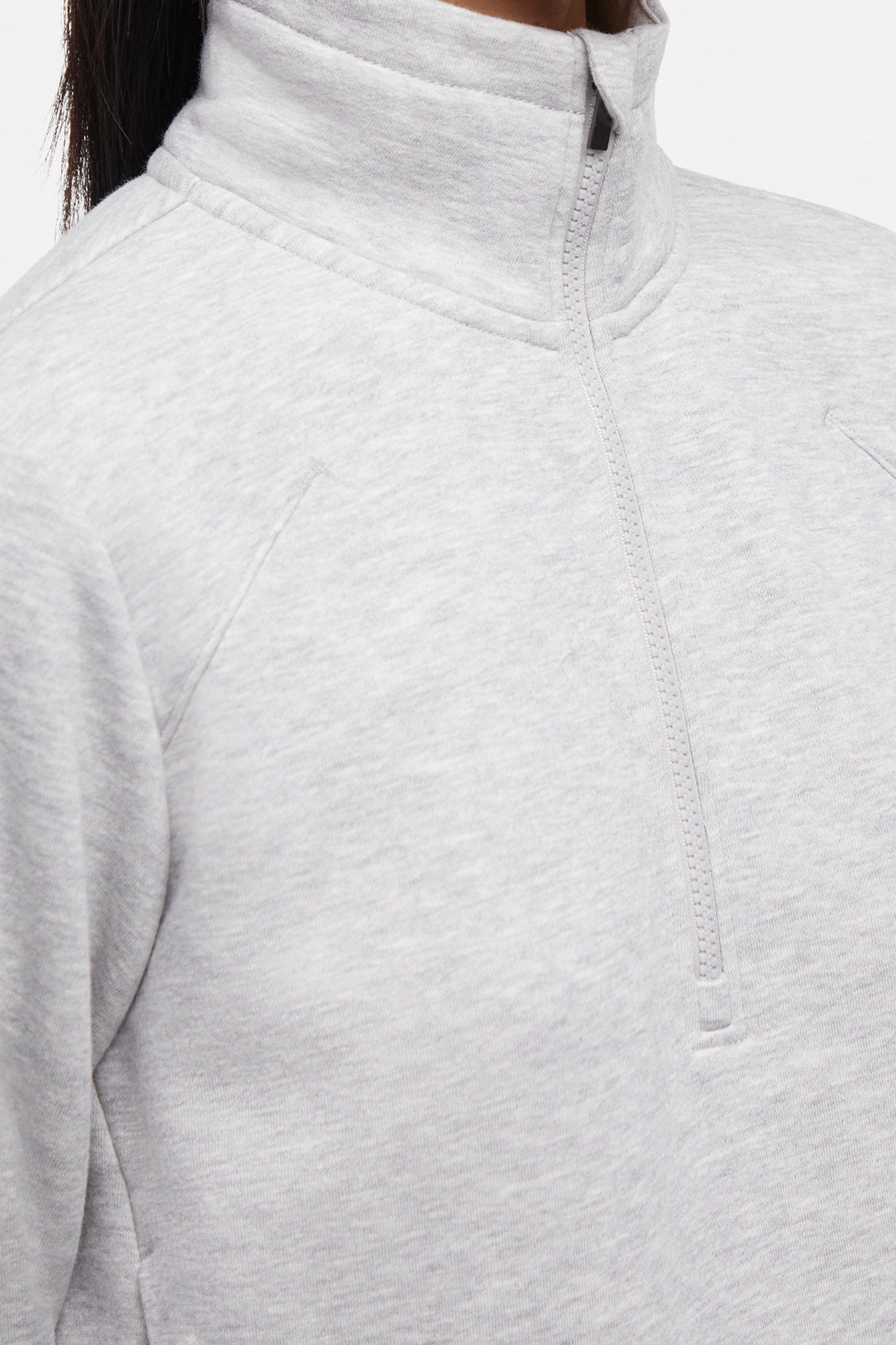 Front close up view of woman wearing heather gray half-zip pullover with thumbholes  on a white background.