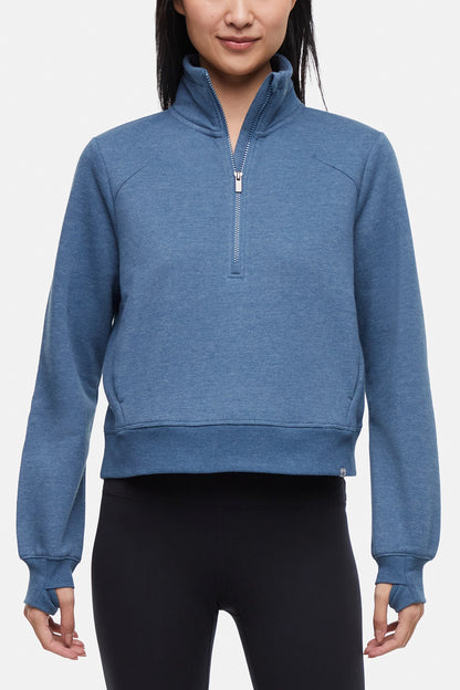 Front view of woman wearing heather blue half-zip pullover with thumbholes on a white background. 