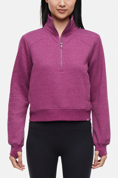 Front view of woman wearing burgundy half-zip pullover with thumbholes on a white background. 