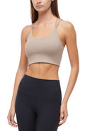 Front view of woman wearing a beige sports bra and black leggings on a white background. #color_taupe-gray