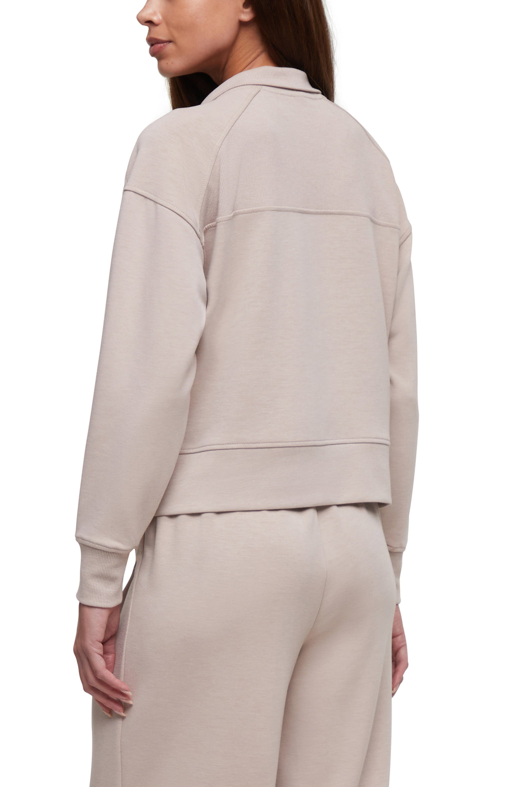 A woman shown from the back wearing a light beige cropped sweatshirt and matching sweatpants against a plain white background.