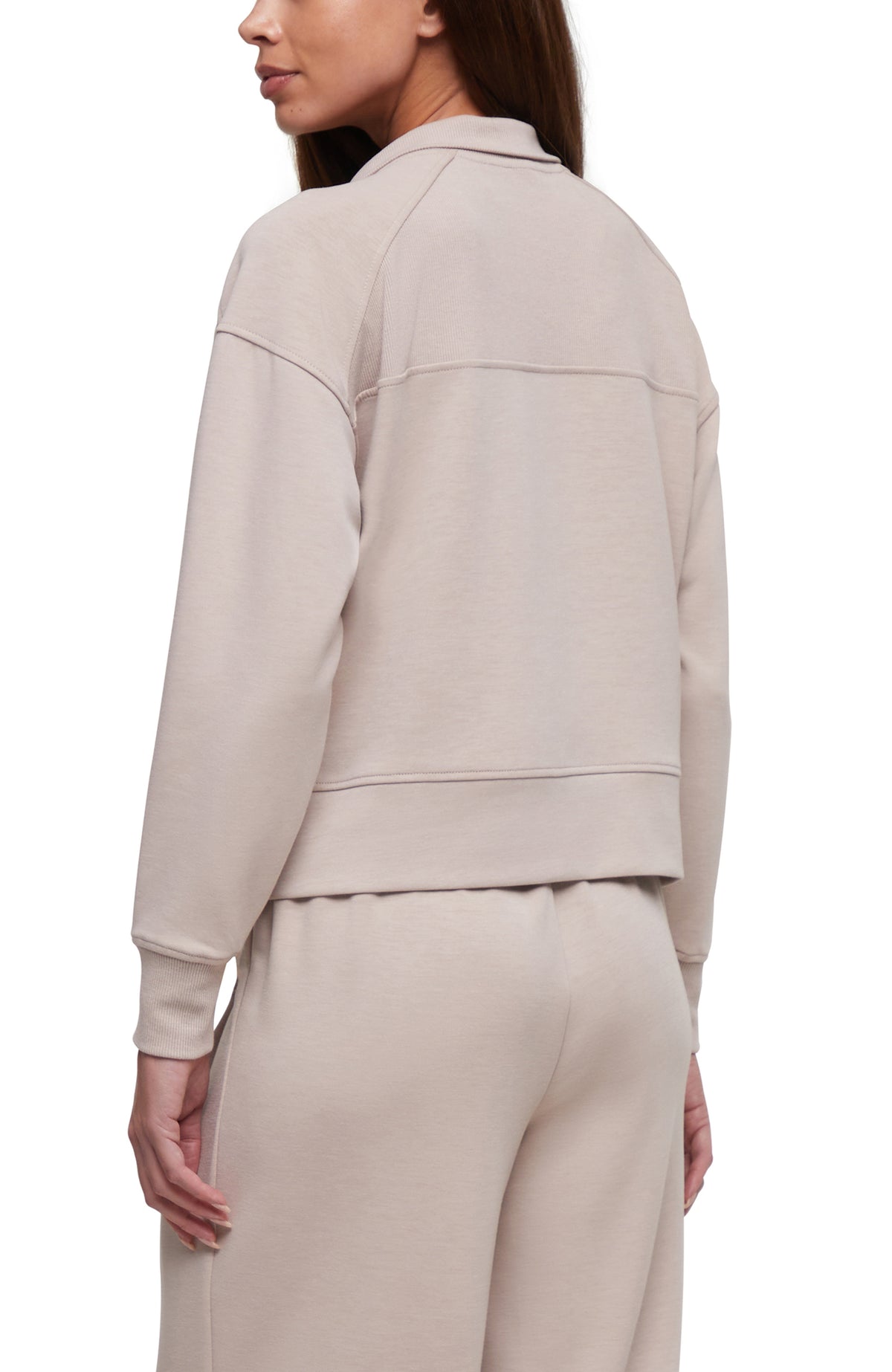 A woman shown from the back wearing a light beige cropped sweatshirt and matching sweatpants against a plain white background.