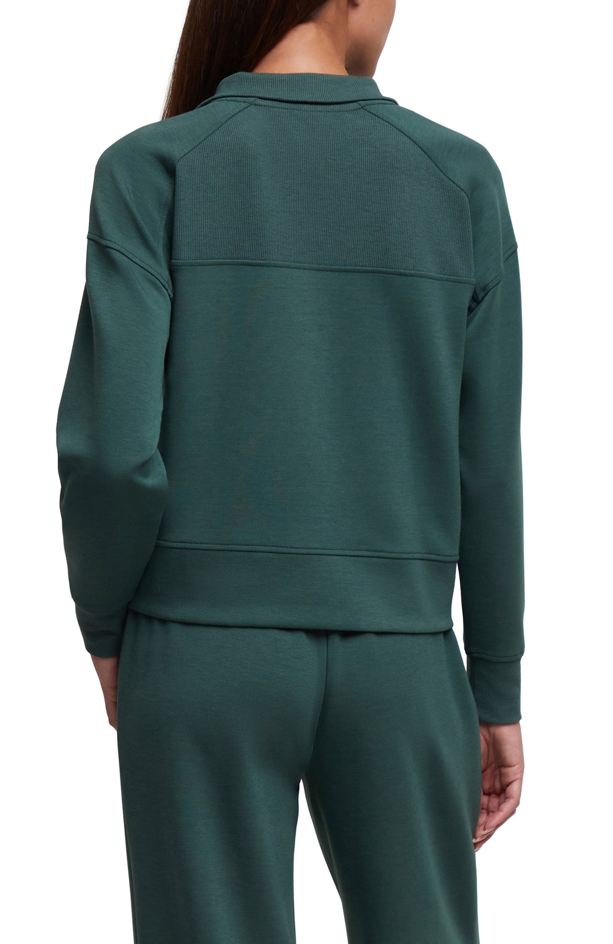 A person shown from the back wearing a dark teal-green long-sleeve sweatshirt and matching sweatpants against a plain white studio background.