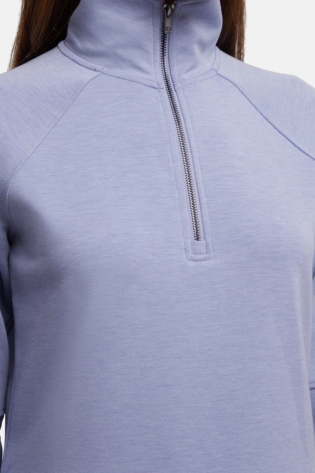 Close-up of a person wearing a light periwinkle blue quarter-zip pullover with a mock neck collar and silver zipper. 