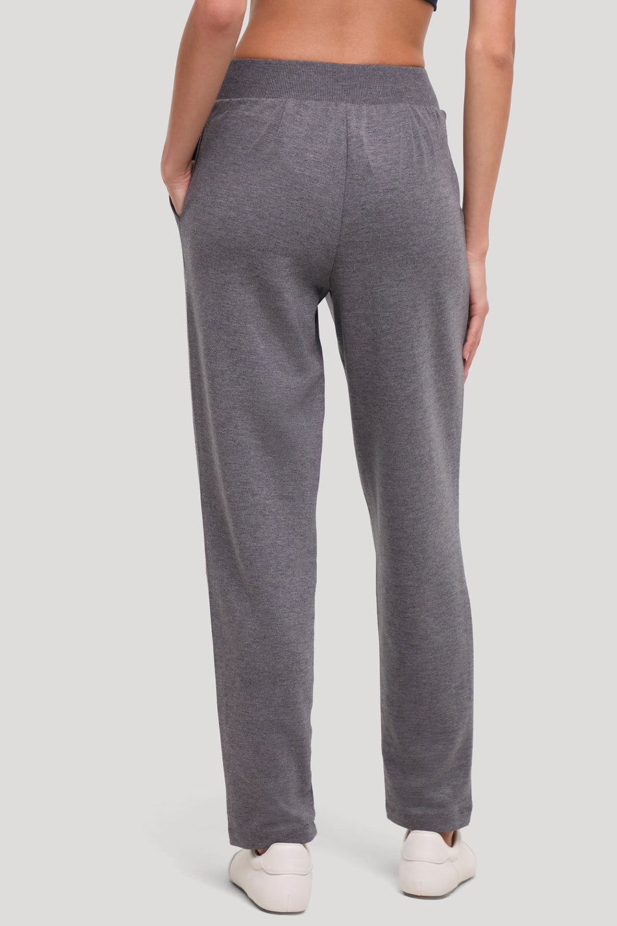 A person shown from the back wearing heather gray lounge pants with an elastic waistband and side pockets, paired with white sneakers, against a light gray studio background. #color_heather-black
