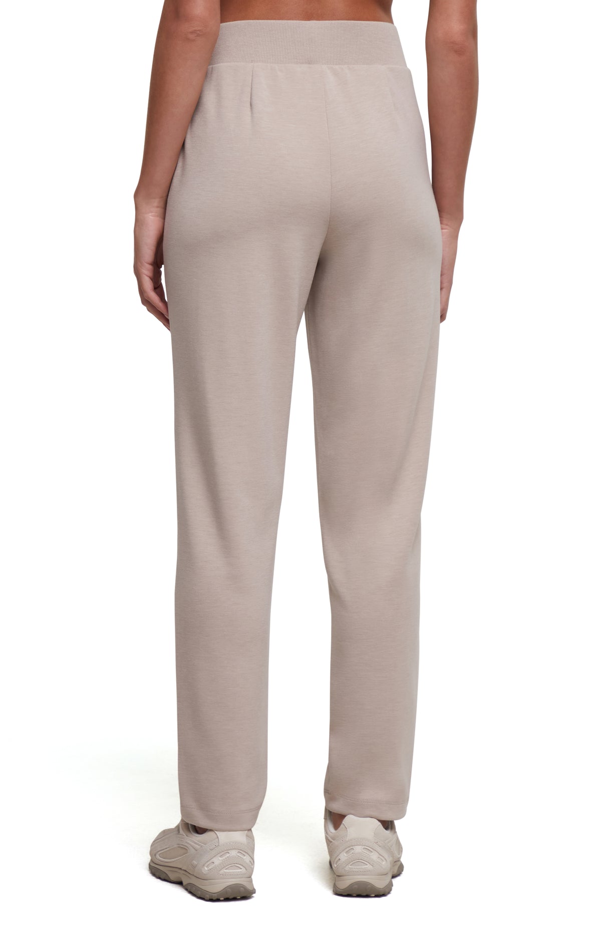 A person shown from the back wearing light beige straight-leg sweatpants and white sneakers against a plain white studio background. #color_heather-atmosphere