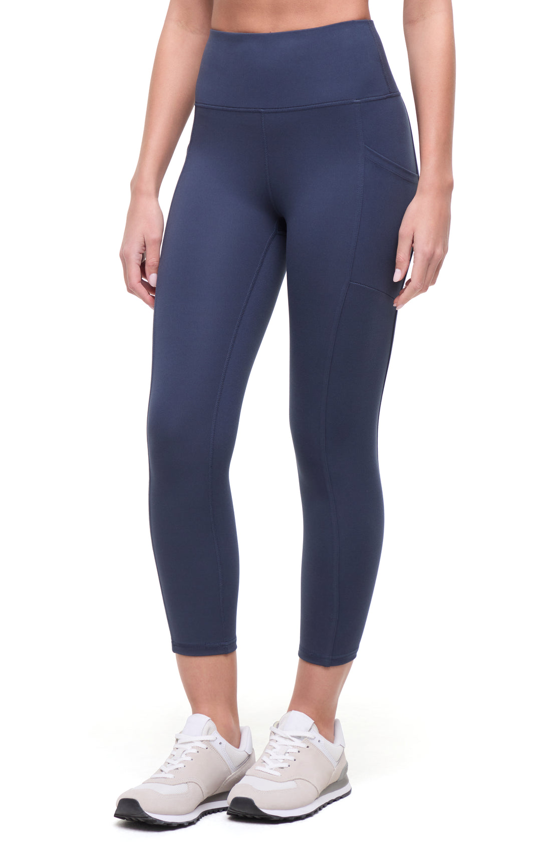 Front view of woman wearing navy blue leggings on a white background. 