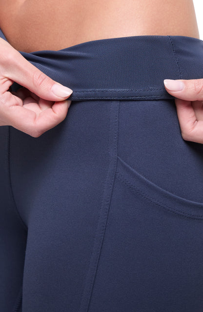 Close up view of woman wearing navy blue leggings showing inner waistband on a white background. 