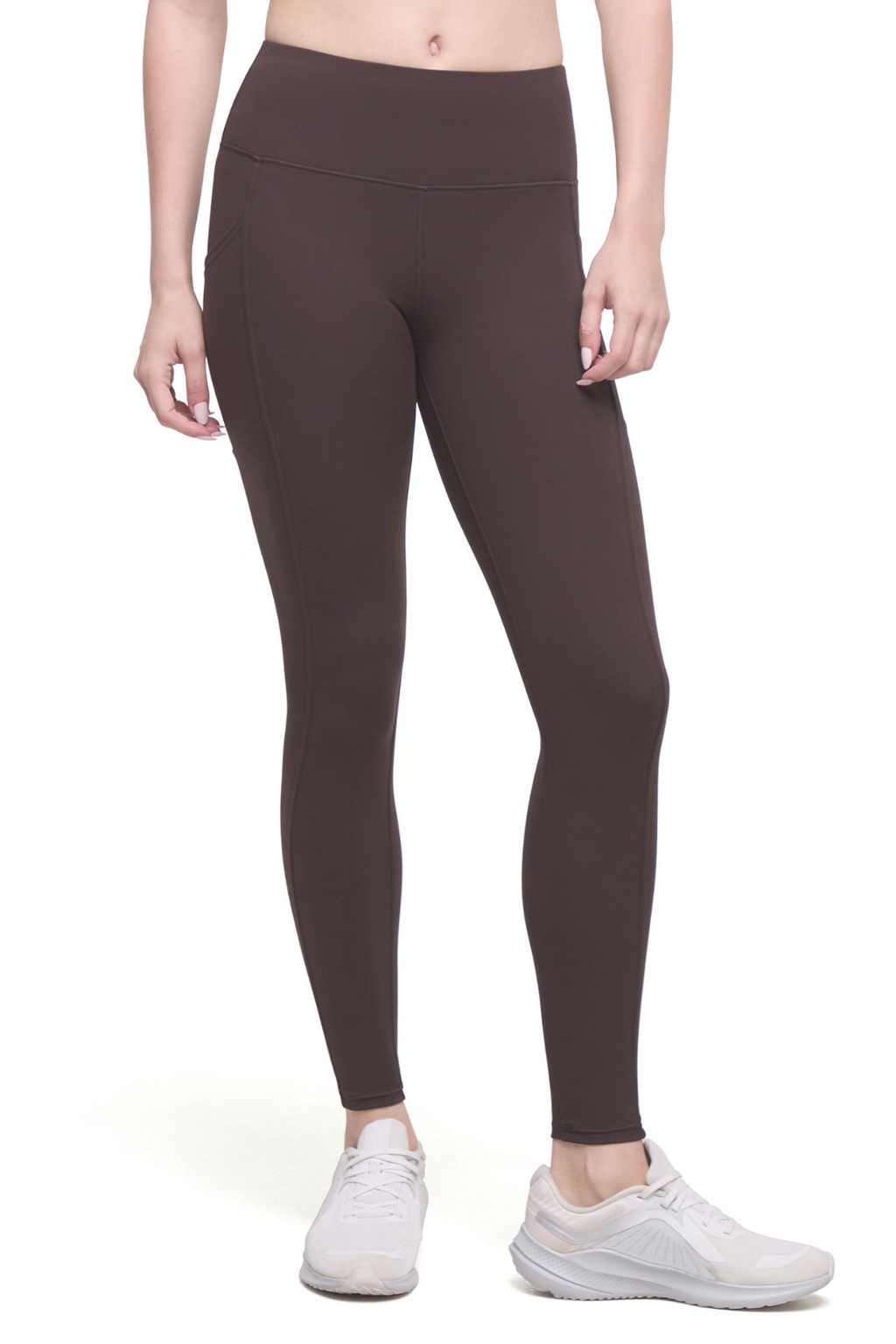 A model wearing dark brown high-waisted leggings and white sneakers, shown from the waist down against a plain white background.