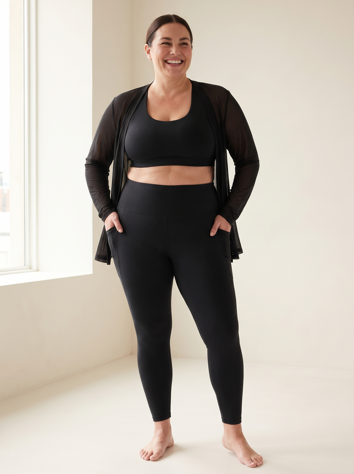 Smiling plus-size woman in black tummy control leggings with pockets and a black sports bra