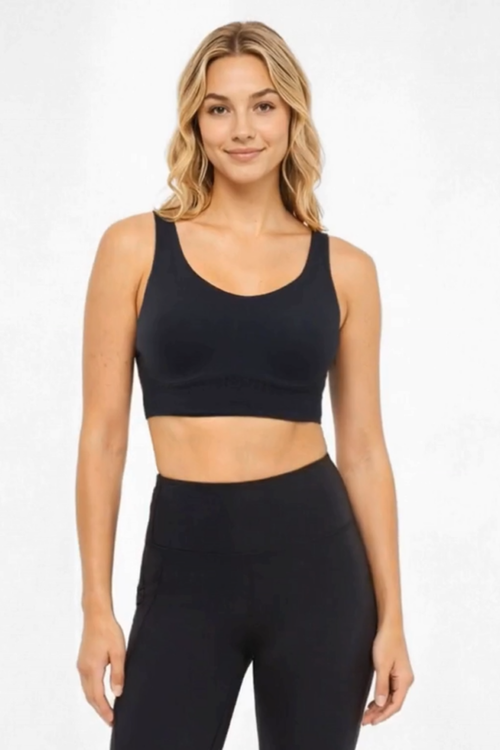 A woman modeling a black scoop-neck athletic crop top and matching black high-waisted leggings against a plain white studio background. #color_black