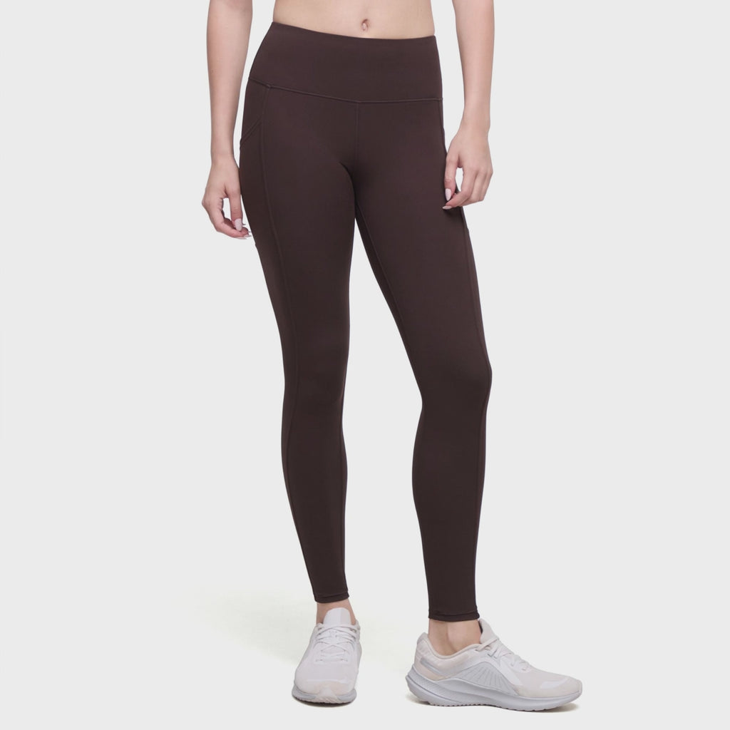 Video of A model wearing dark brown high-waisted leggings and white sneakers, shown from the waist down against a plain white background.
