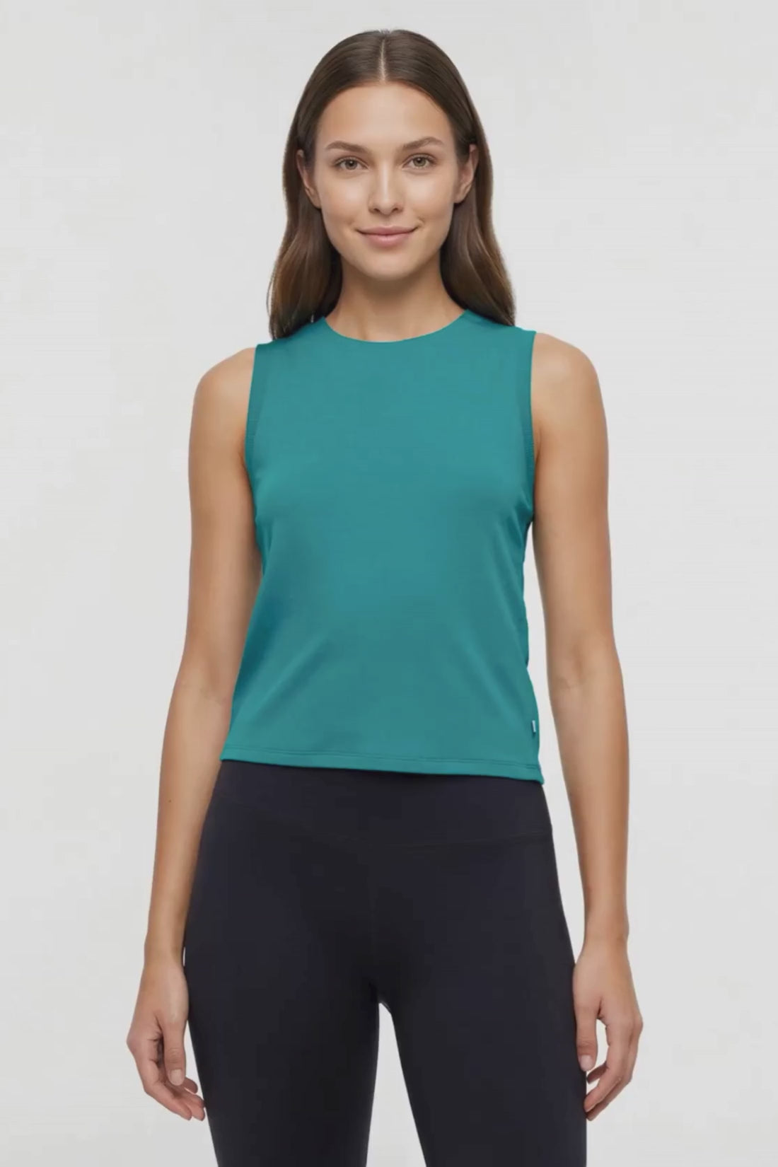 Video view of woman wearing a teal sleeveless top and black leggings on a white background. #color_quetzal-green