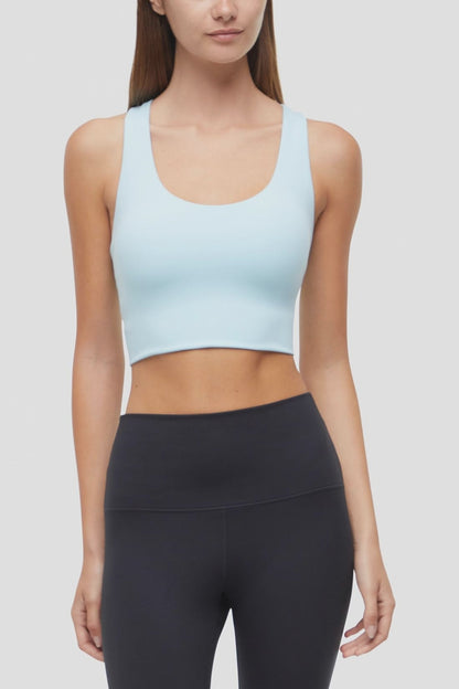 Video view of woman wearing a light blue sports bra and black leggings on a white background. 