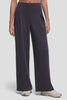 Video of a model wearing high-waisted, wide-leg trousers in a dark charcoal gray color with front pleat details, paired with beige sneakers, against a light gray studio background. #color_phantom