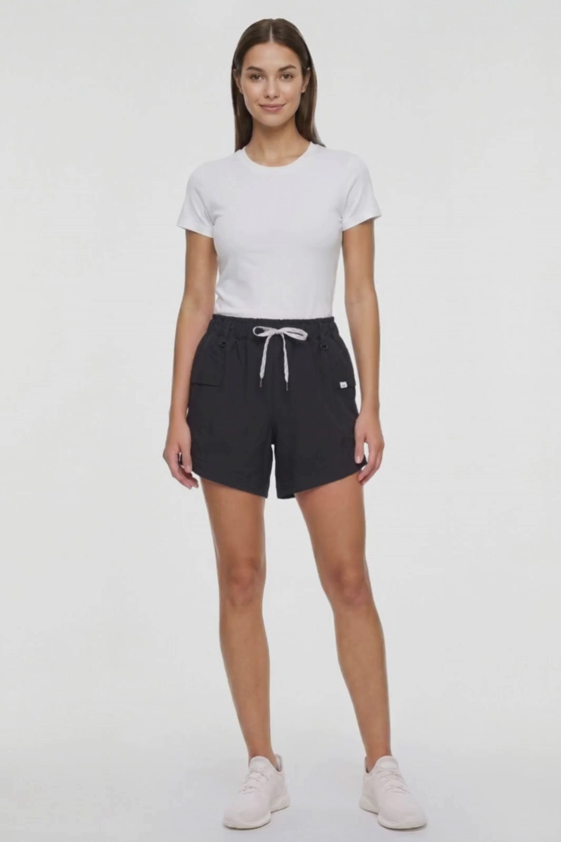 Video view of woman wearing black shorts with white drawstring waist and side pocket and white sneakers on a white background. #color_black