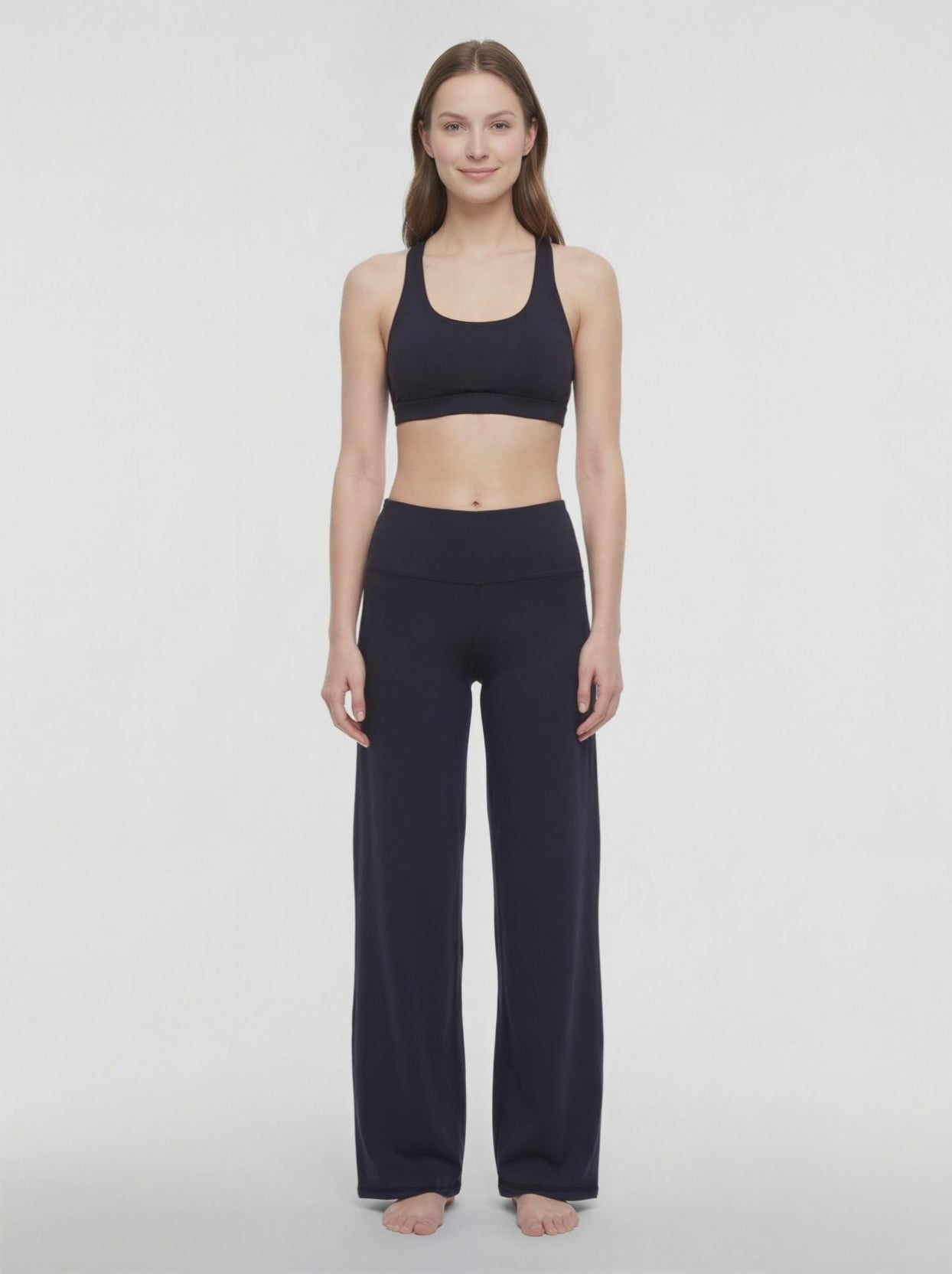 Video view of woman wearing black yoga pants on a white background. 