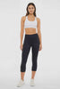 Video view of woman wearing black capris and white sneakers on a light gray background. #color_black
