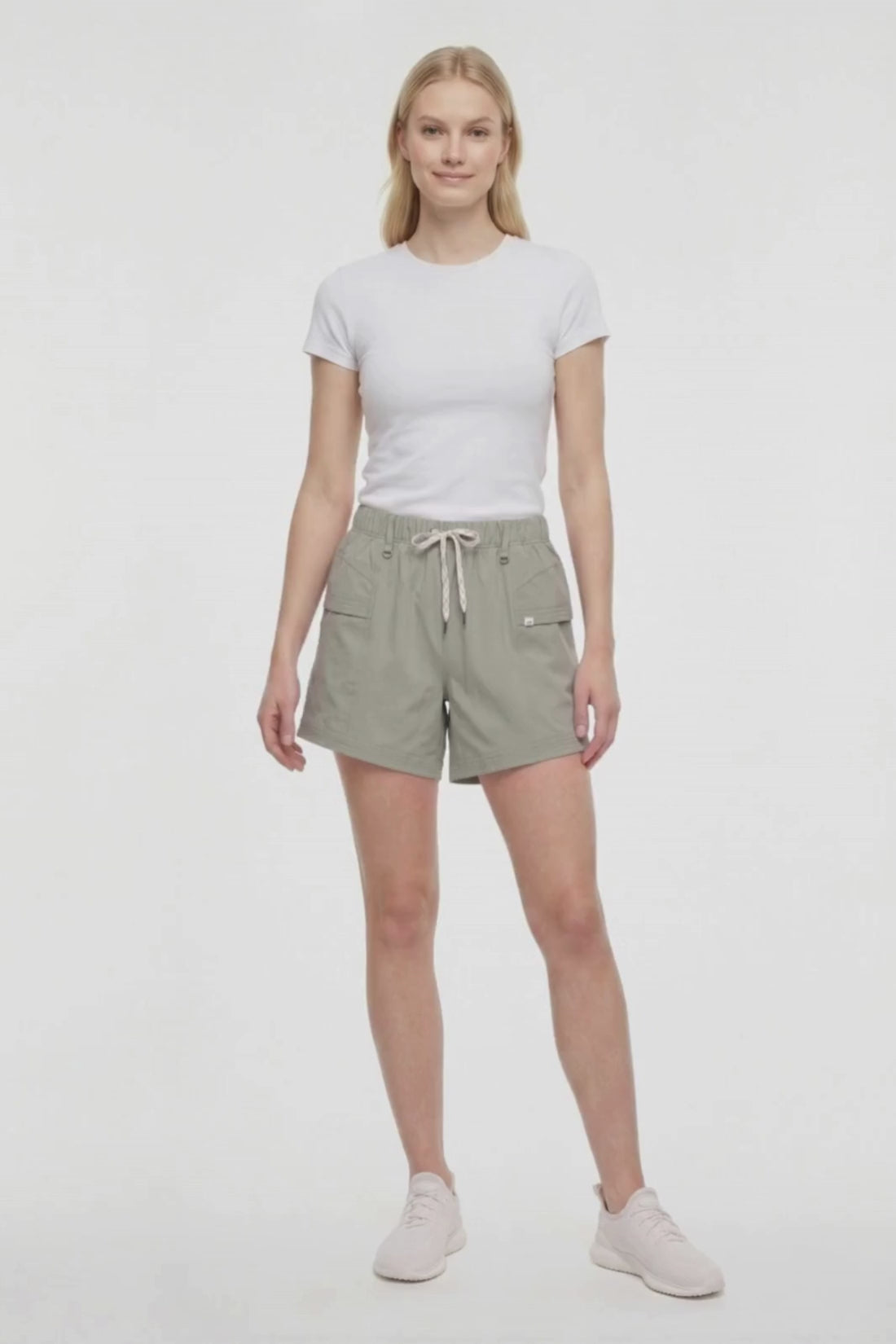 Video view of woman wearing sage green shorts with white drawstring waist and white sneakers on a white background. #color_shadow