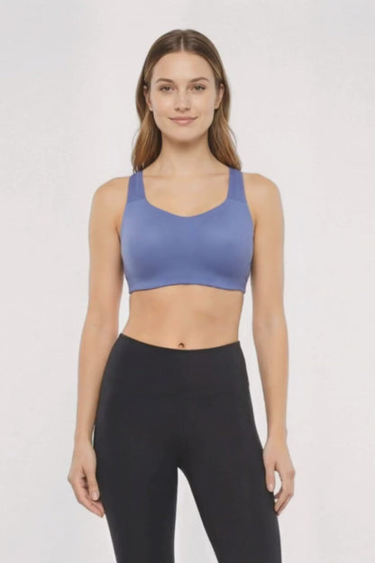Video view of woman wearing a blue sports bra and black leggings on a white background. 