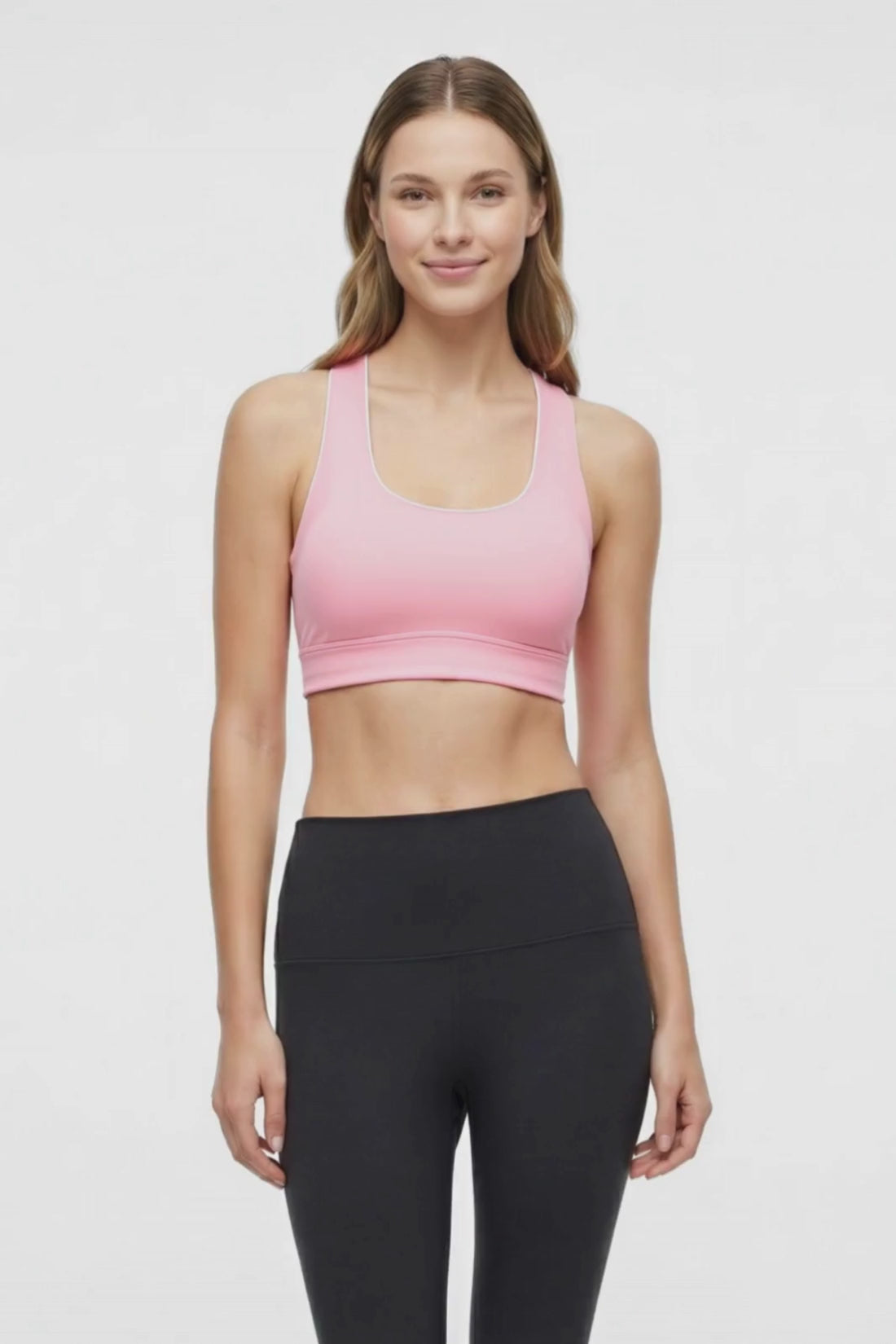 Video view of woman wearing a light pink sports bra with white trim and black leggings on a white background. #color_rosy-future