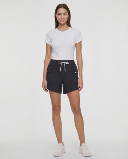 Video view of woman wearing black shorts with white drawstring waist and side pocket and white sneakers on a white background. 