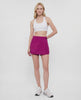 Video of woman wearing a magenta purple skort with waist clasp and white sneakers on a white background. #color_magenta-purple
